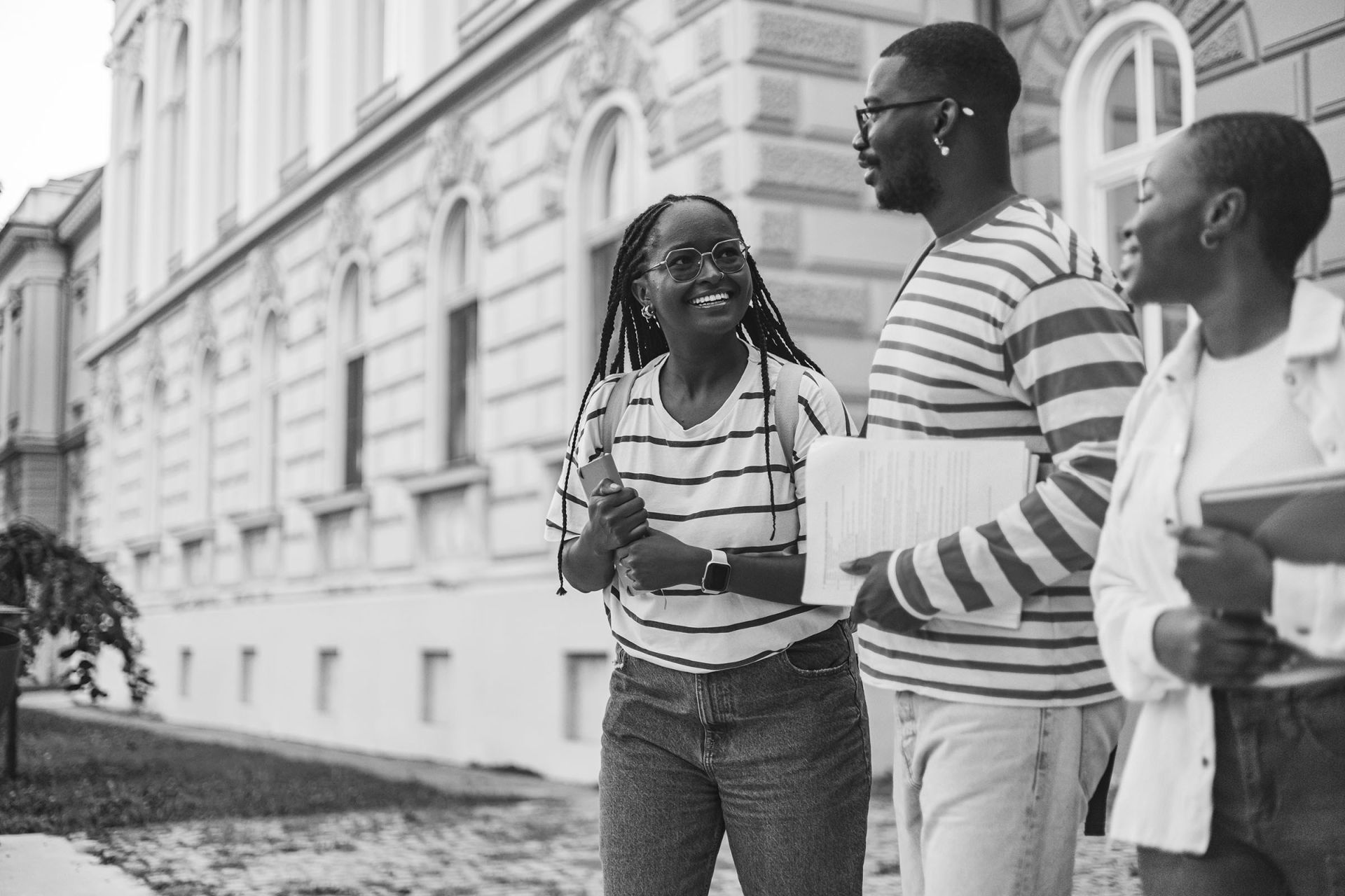 Three black students walking in front of a historic building.